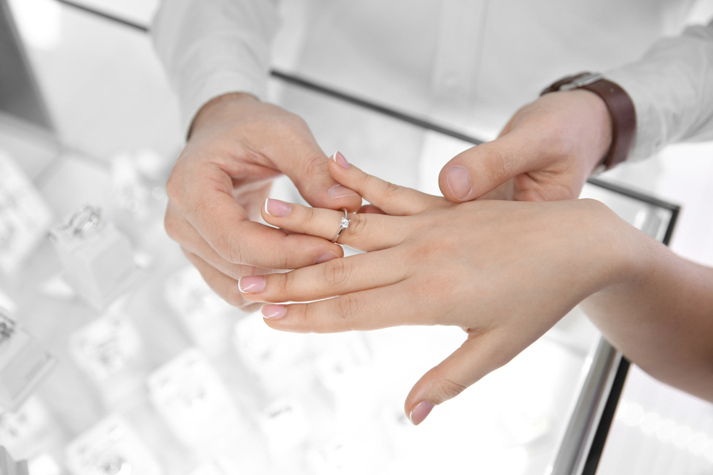宝石店で婚約指輪を試着するカップル