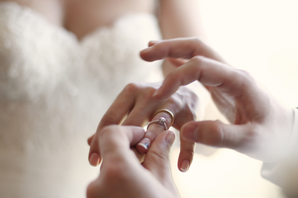 婚約指輪と結婚指輪をはめてあげているカップル