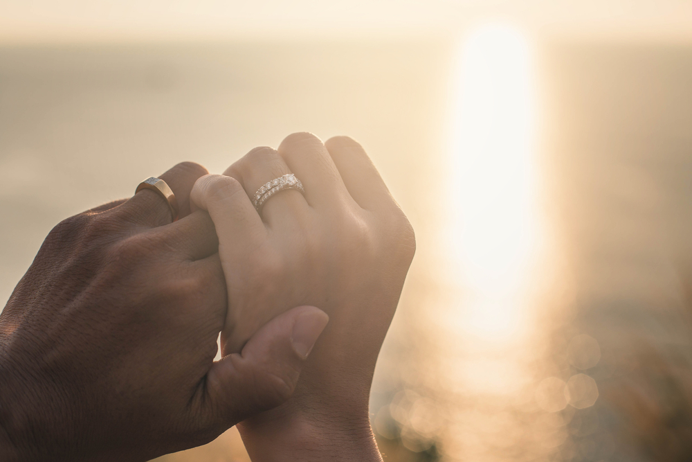 婚約指輪と結婚指輪をみにつけるカップル