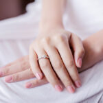 シンプルな婚約指輪をまとう女性の手