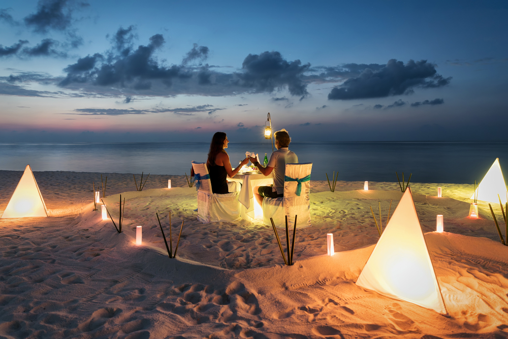 海外旅行先のビーチでロマンチックなディナーを過ごすカップル