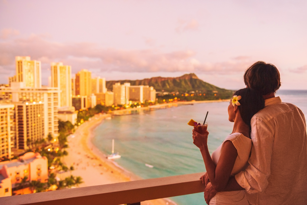 ハワイのワイキキビーチを眺めながらロマンチックな旅行をするカップル