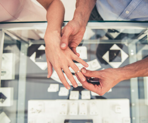 宝石店で婚約指輪を試着するカップル