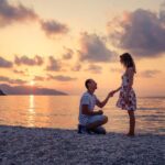 海外リゾートビーチのサンセットでプロポーズするカップル