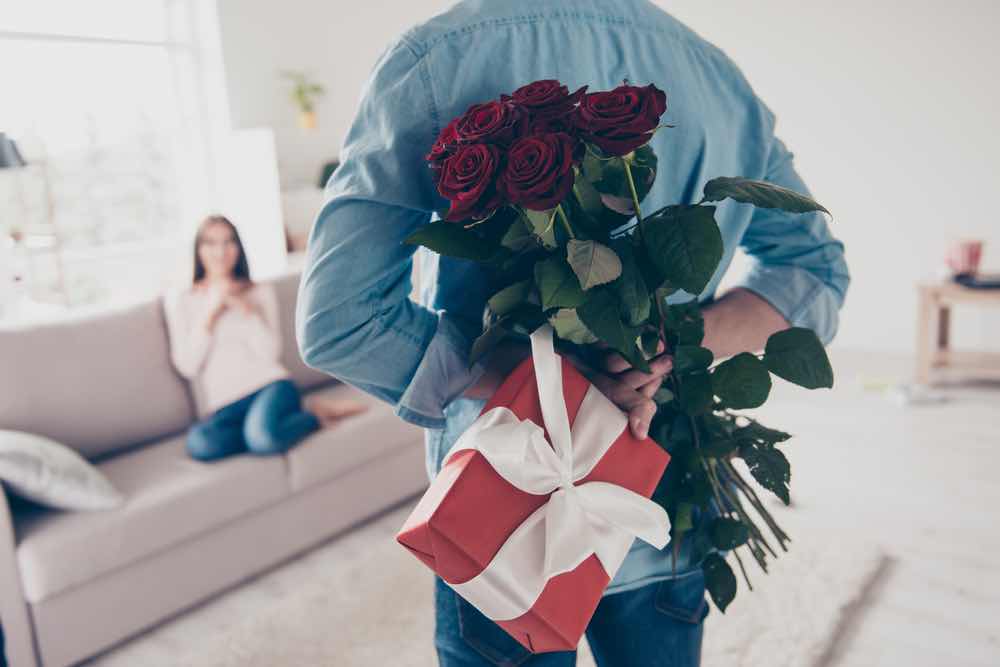 サプライズにバラの花束をプレゼントしようとするカップル